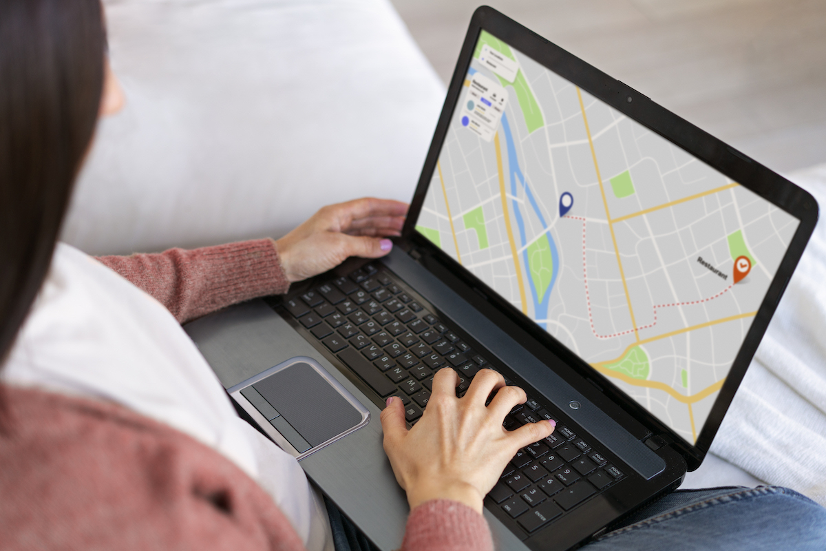 woman holding laptop looking at a location on Google Maps